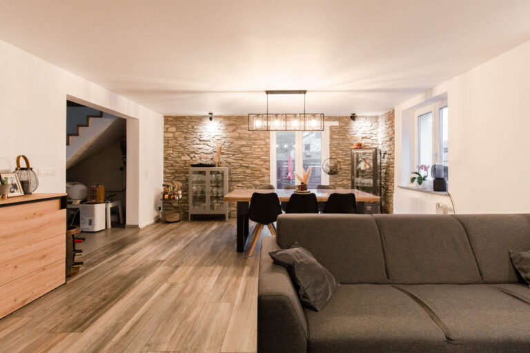 Umbau Appartement: offener Wohnbereich mit Natursteinwand und Esstisch