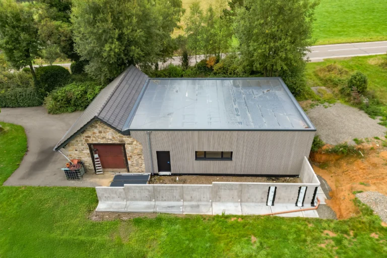 Hallenanbau: neue Halle mit Holzfassade an einem Natursteingebäude, Luftaufnahme