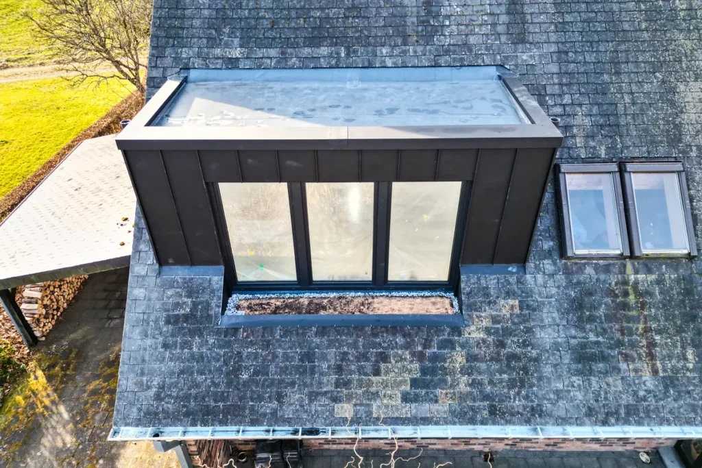 Luftbild: neue, dunkel verkleidete Dachgaube mit dreiteiligem Fenster, daneben zwei Dachfenster