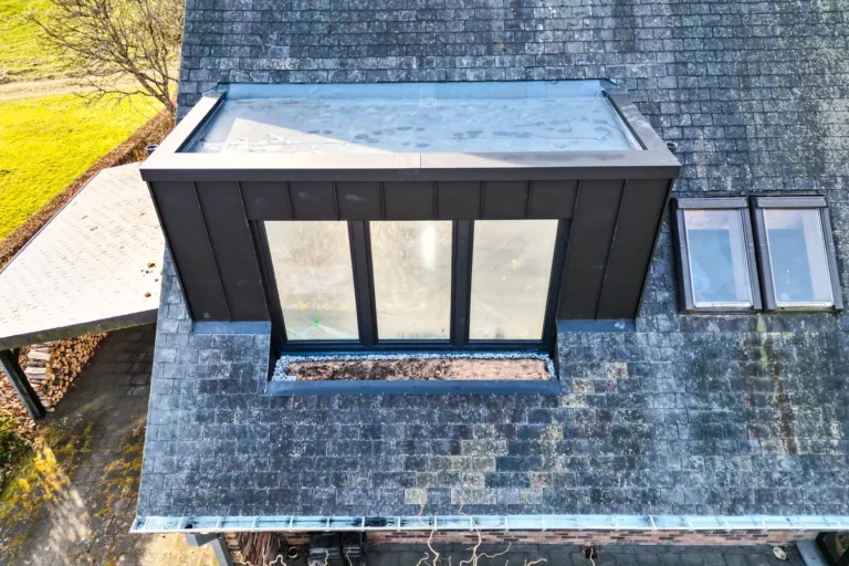Luftbild: neue, dunkel verkleidete Dachgaube mit dreiteiligem Fenster, daneben zwei Dachfenster
