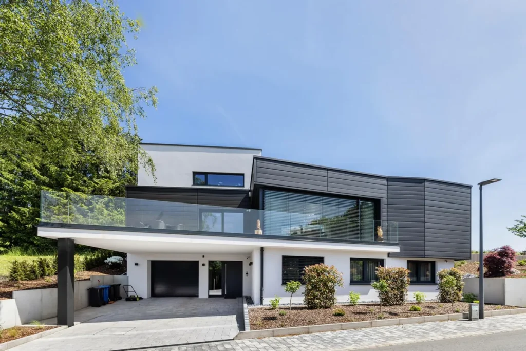 Zweigeschossiges Wohnhaus mit dunkler und weißer Fassade sowie überdachtem Stellplatz