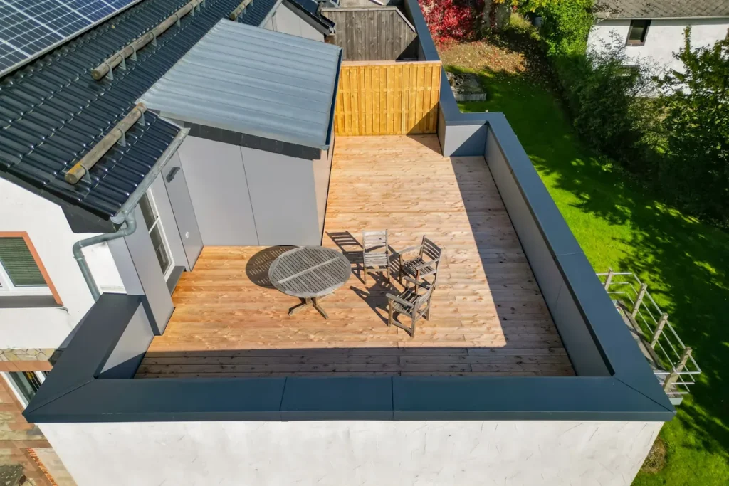Dachterrasse mit Holzbelag, Sitzgruppe und mit Trespa-Platten verkleideter Brüstung, Luftaufnahme