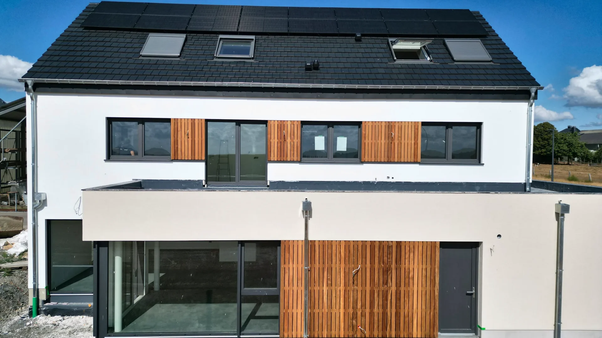 Ansicht von vorn mit Holzfassade zwischen den Fenstern und großen Glasflächen im Erdgeschoss
